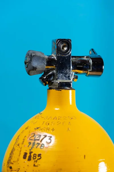 Vintage żółty stalowy zbiornik do nurkowania z zaworem j na niebieskim tle — Zdjęcie stockowe