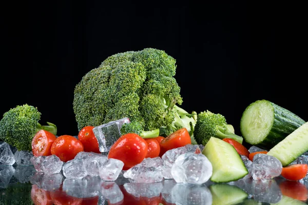 氷のキューブと砕いた氷と黒の背景に野菜 — ストック写真