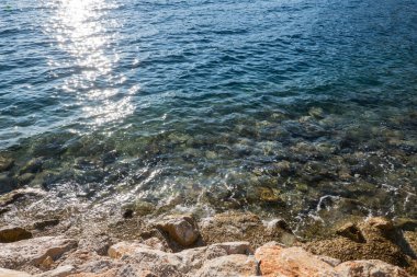 Üzerinde mavi deniz olan kayalık resife bakan yatay bir fotoğraf..