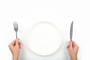 Çatallı, bıçaklı ve boş plakalı bir kadın beyaz arka planda, üst tarafta..