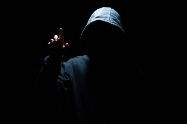 Maskeli hacker karanlık arka plana karşı sanal ekranla çalışıyor. Siber güvenlik ve saldırı kavramı.