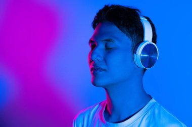 Müzik dinliyordum. Mor renkli neon ışıkta arka planda Asyalı bir adamın portresi. İnsan duyguları kavramı.