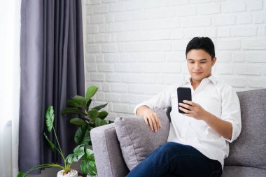 Heyecanlı gülümseyen adam telefon ekranına bakıyor, mobil uygulama kullanıyor, sosyal ağda mesaj yazıyor, haberleri okuyor, e-posta yazıyor..