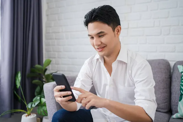 Man Zittend Grijze Bank Met Smartphone Met Lachend Gezicht Lifestyle — Stockfoto