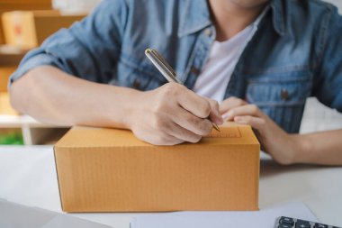 Genç Asyalı adam posta kutularına müşteri adresleri yazıyor. E-ticaret ve internet teknolojisi kavramı.
