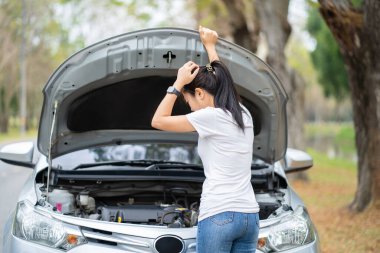Bozuk arabasının yanında Asyalı bir kadın. Hasarı görmek için kaputu açtı. O şüpheli bir elle kafasına dokundu..