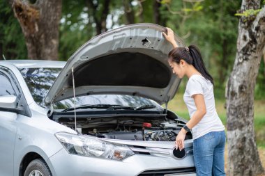 Bozuk arabasının yanındaki kadın hasarı görmek için kaputu açtı. Kadın görüntüsü.