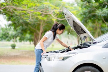 Güzel Asyalı kadın yolda bozuk bir arabayı tamir ediyor..