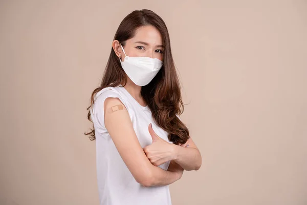 마스크를 착용하고 마스크를 이시아인 여성의 백신을 티셔츠를 붕대를 배경에 고립되어 — 스톡 사진