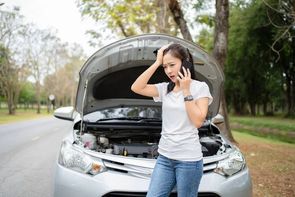 Black long hair asian young woman talking on cellphone after car breakdown trouble problem mechanic.
