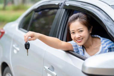 Happy beautiful woman driver holding keys her new car with smiling. Young woman with the keys at the car. Concept of having a new car.