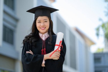 Mezuniyet gününde mezun olmuş öğrenciler. Kollarını kavuşturup diplomasını elinde tutuyordu..