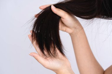 Beyaz arka planda siyah, zarar görmüş saçlar tutan eli kapat..