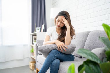 Kanepede gözlerini kapayan genç Asyalı kadınlar baş ağrısından muzdaripler..