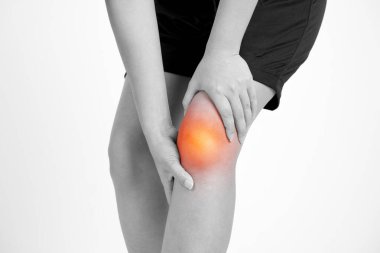 Diz ağrısı olan bir genç kadın portre görünümü. Beyaz arka plan üzerinde izole. Siyah ve beyaz fotoğraf kırmızı nokta.