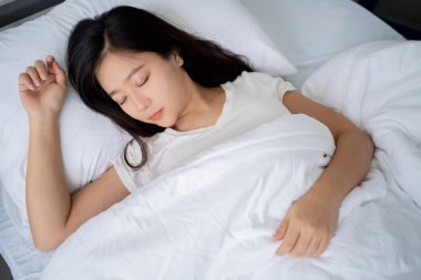 Kadın beyaz bir yatakta uyuyor..