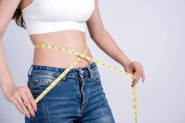 テープメジャーを持つジーンズの女性は薄い体を示しています 減量と痩身の概念 — ストック写真