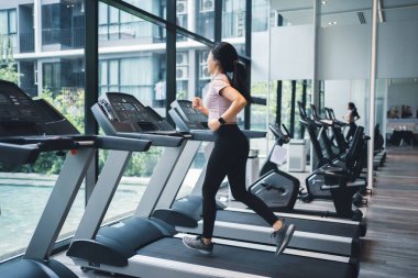Side view of beautiful sports man running on treadmill in gym.