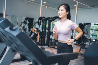 Koşu bandında koşan ve en sevdiği şarkıyı dinleyen bir kadının yan görüntüsü.