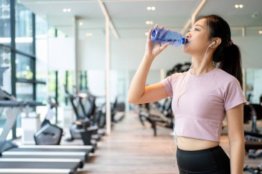 Güzel bir kadın spor salonunda kas çalışırken su içiyor..
