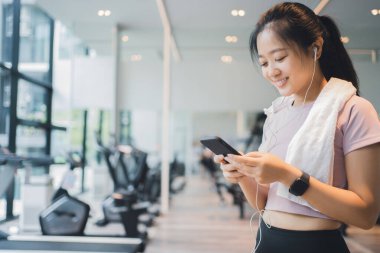 Spor salonunda akıllı telefon kullanan atletik bir kız, yaşam tarzı ve sağlıklı konsept.