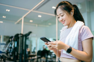 Spor salonundaki akıllı telefondan müzik dinleyen kız ağır egzersizden sonra.
