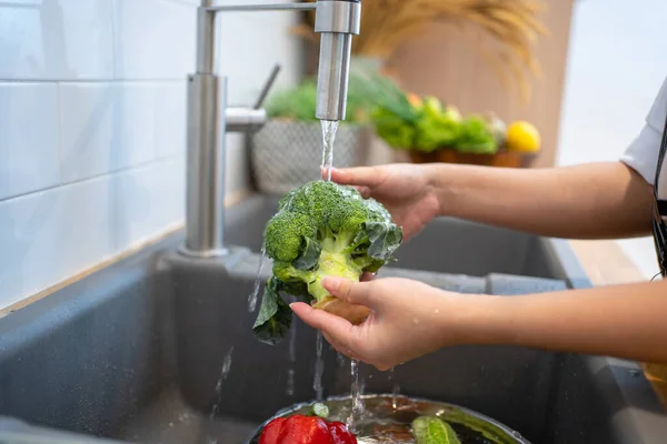 People washing vegetables in the kitchen.