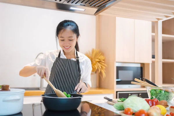 Cooking happy woman wear apron in kitchen. She is cooking in the kitchen