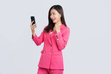 Portrait of a beautiful Asian girl wearing a pink uniform. She feels happy or shocked and holds a smart phone with blank black screen on white background. product presentation concept