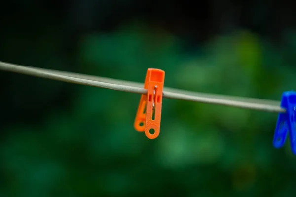 Parlak turuncu bir mandal ipte asılı.