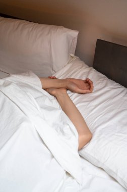 Woman sleeping in the bed under white sheet.
