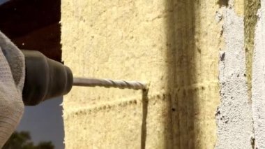 Bir matkabın yakın çekimi duvarı deliyor.