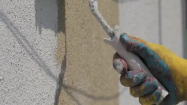 Eldiven giyen işçi duvarı boyar. Beyaz boya.