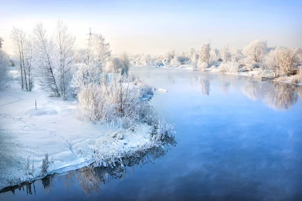 Trees on the banks of the river in white snowy frost on the banks of the river in the Moscow region on a winter sunny evening