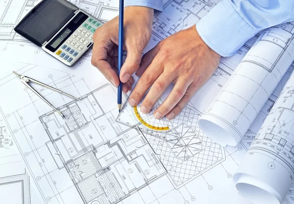 Hands with tool and project drawings — Stock Photo, Image