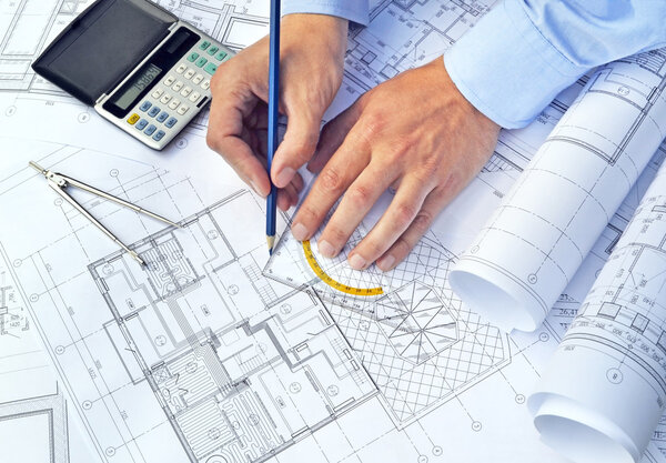 Руки с инструментами и проектными чертежами
