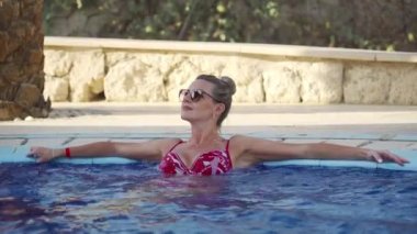 Havuzdaki kadın suyla hoş bir masajdan hoşlanıyor. Sıcak bir yaz gününde dinlenmek.