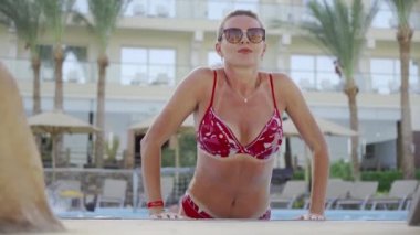 Orta yaşlı bir kız havuzdan atlıyor. Otelde dinleniyor ve eğleniyor..