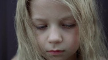 Beyaz saçlı küçük bir kızın yüzünde hüzünlü bir ifade. Bir çocuğun üzgün gözleri. Yakın plan..