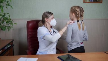 Bayan bir doktor okul çağındaki küçük bir kızın boğazını muayene ediyor. Tıbbi muayene, çocuk sağlığı..