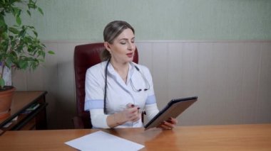 Dost canlısı kadın doktor, hastaya tablet kullanılarak tedavi edilme sorununu açıklıyor. Beyaz önlüklü bir tıp uzmanı..