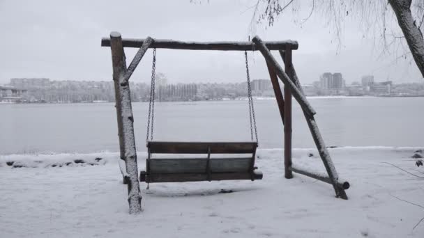 雪に覆われた川沿いの一時停止ベンチ 冬に出発した休憩所 — ストック動画