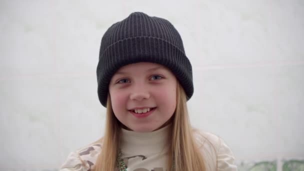 Веселая Улыбающаяся Девушка Настраивает Свою Зимнюю Шляпу Глядя Камеру — стоковое видео