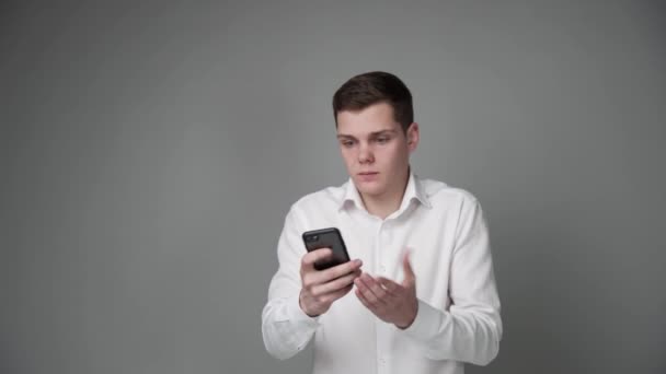 不満男とともにスマートフォンで彼の手に灰色の背景. — ストック動画