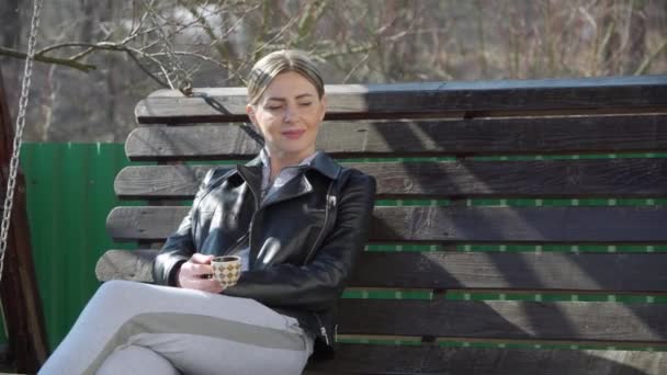 Žena Pije Kávu Lavičce Zahradě Užívá Teplých Paprsků Jarního Slunce — Stock video