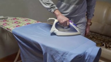 Bir ev hanımı günlük aktivitelerle meşgul olur. Bir erkeğin gömleğini ütü masasına ütüler..