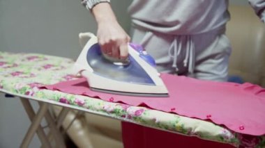 Bir ev hanımı günlük aktivitelerle meşgul olur. Bir erkeğin gömleğini ütü masasına ütüler..