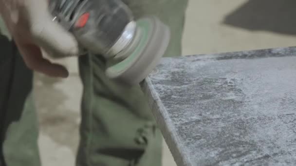 Broušení žulového kamene bruskou. Ruce mistra, který obratně používá pracovní nástroj. Detailní záběr.