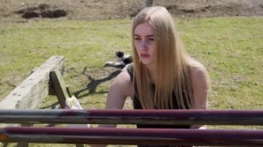 Genç bir kız evinin arka bahçesinde boruları boyuyor. Arka bahçede çalış..