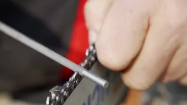 Tahta kesmek için zincir dişlerini biliyorum. Benzo veya elektrikli testerelerin bakımı. Efendinin ellerine yakın çekim. Seçici odak.